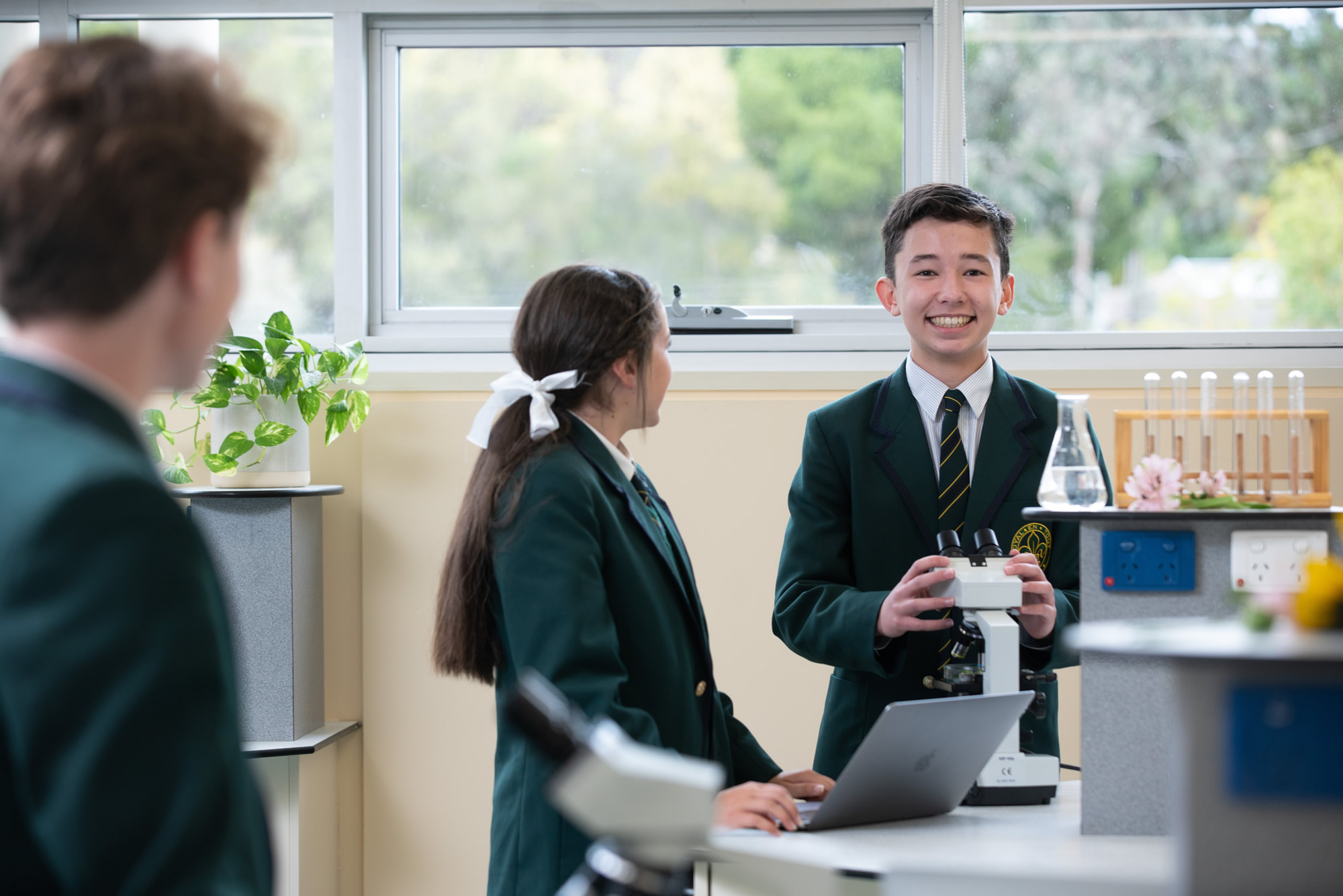 Students working together in the laboratory at Mercedes College with microscopes and test tubes.